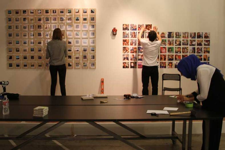 Intersection for the Arts interns install the 100 Days, 100 Portraits prints alongside the work of artist Joan Osato in late October for the Califas Festival, which runs Nov. 1-17 in San Francisco. (Photo by Rebecca Ahrens)